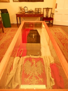 The lid of the coffin used to transport General's body from Gibraltar to England; the Polish Naval Ensign used to cover the coffin and Polish National flag that covered the coffin during the funeral.